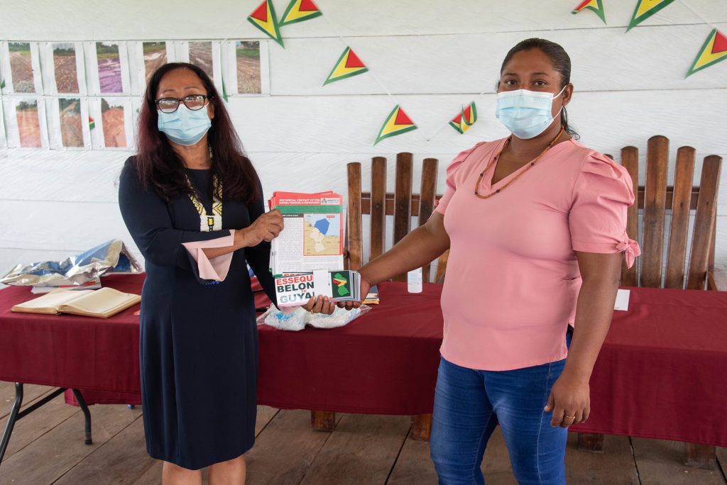 Minister of Amerindian Affairs, Hon. Pauline Sukhai hands over a quantity of educational materials to Toshao of Baramita, Ms. Sharmain Rambajue