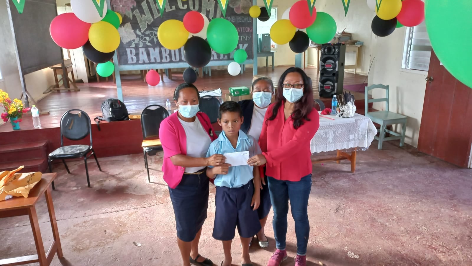 Minister of Amerindian Affairs, Hon. Pauline Sukhai M.P hands over the "Because We Care" grant to a student's parent