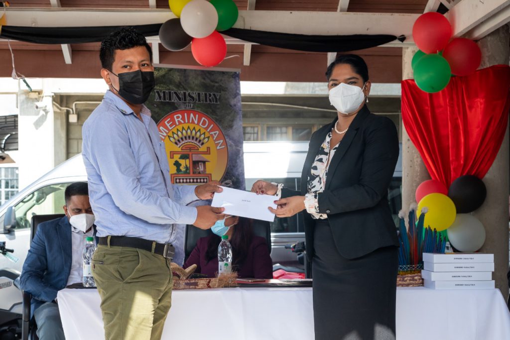 Participant, Gyarth Taylor being presented with his consolation prize by Hon. Minister of Public Service Sonia Parag