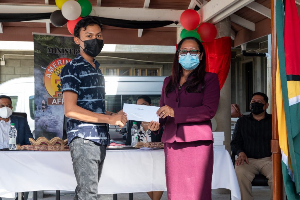 Winner of the Theme Competition, orlan Thomas receiving his prize from Hon. Minister Pauline Sukhai, Minister of Amerindian Affairs
