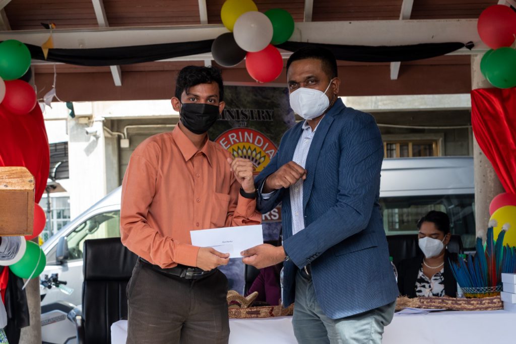 Participant, Ryan Bacchus being presented with his consolation prize by Hon. Minister of Local Government and Regional Development, Nigel Dharamlall